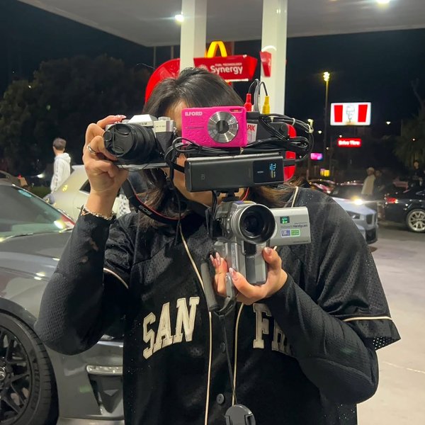 Clarissa holding her camera and camcorder rig at a car meet